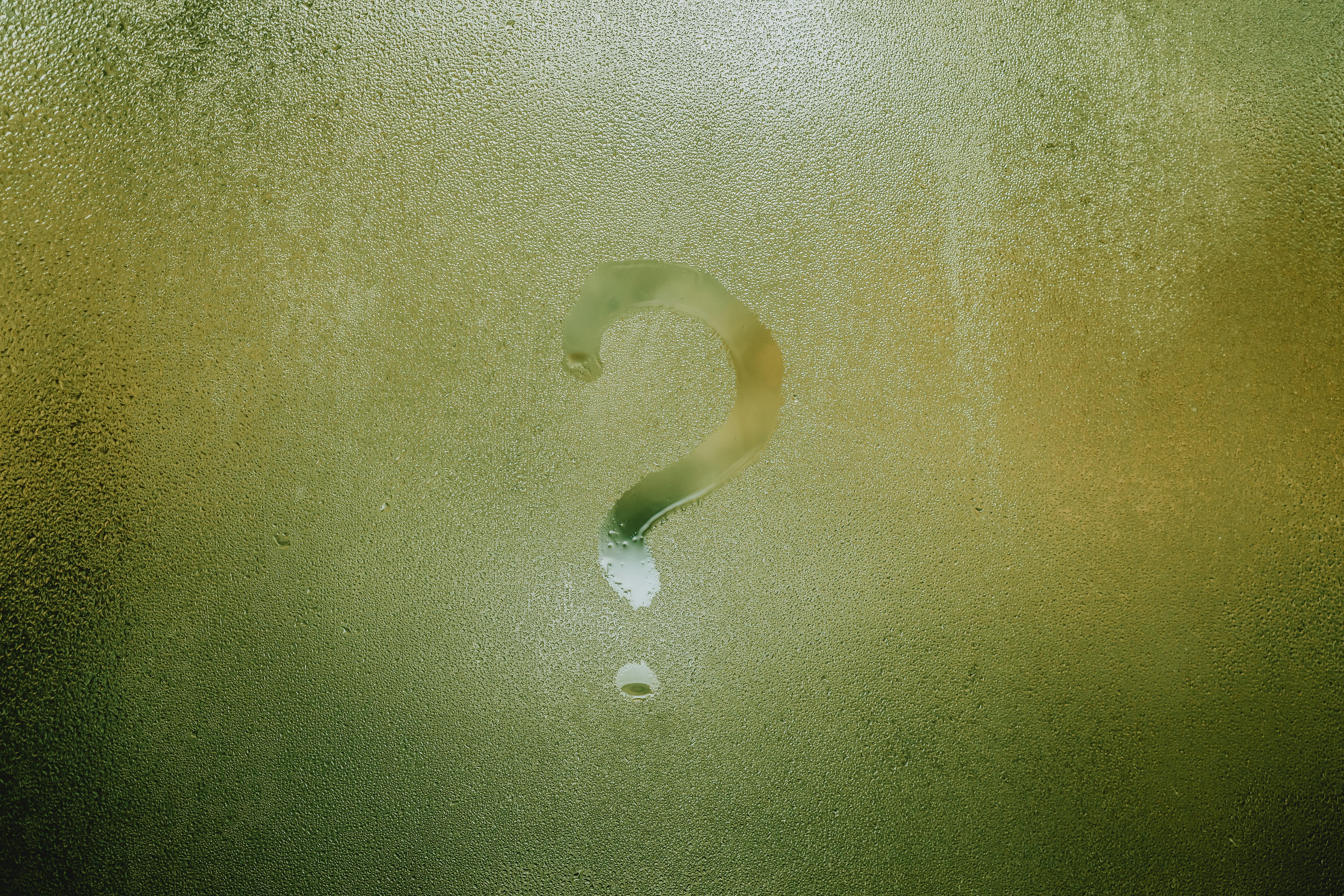 Misted green glass with a hand-drawn question mark, suggesting frequently asked questions and gentle curiosity.